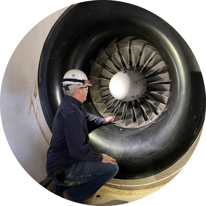 A peaking plant operator kneeling next to a turbine